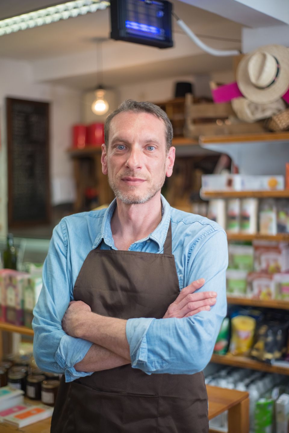 Shop owner in apron with arms crossed